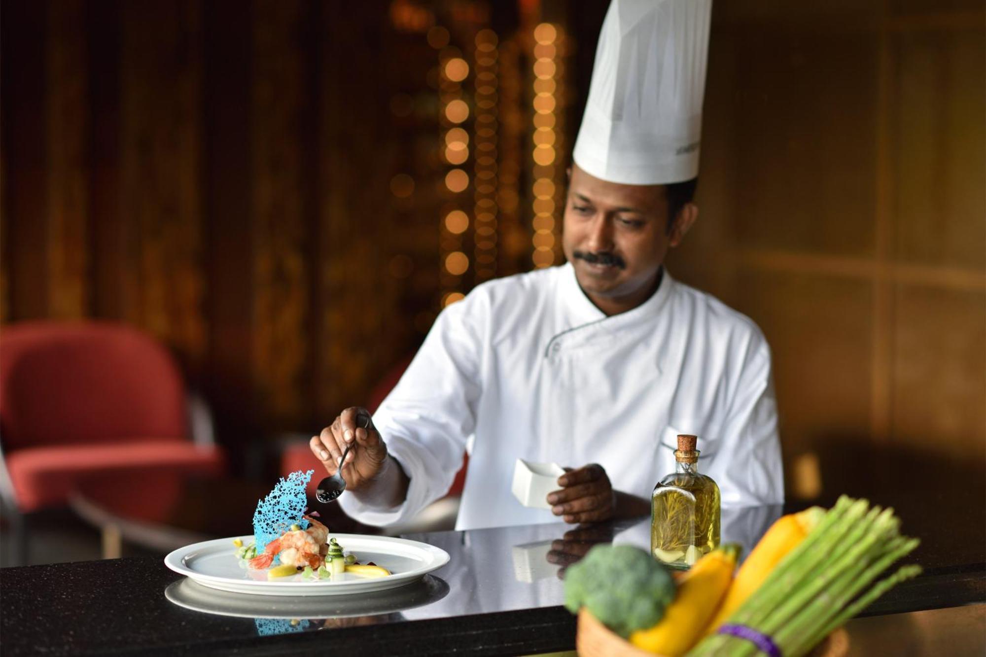 Готель Le Meridien Нью-Делі Екстер'єр фото A chef seasoning a dish